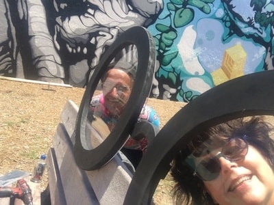 Two artists beside the circular frame bench sculpture with mural — Clematis Street Bench Project