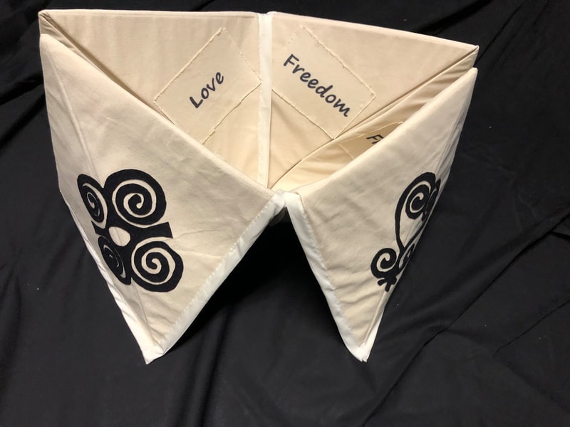 Upright origami fabric sculpture with spiral motifs and text