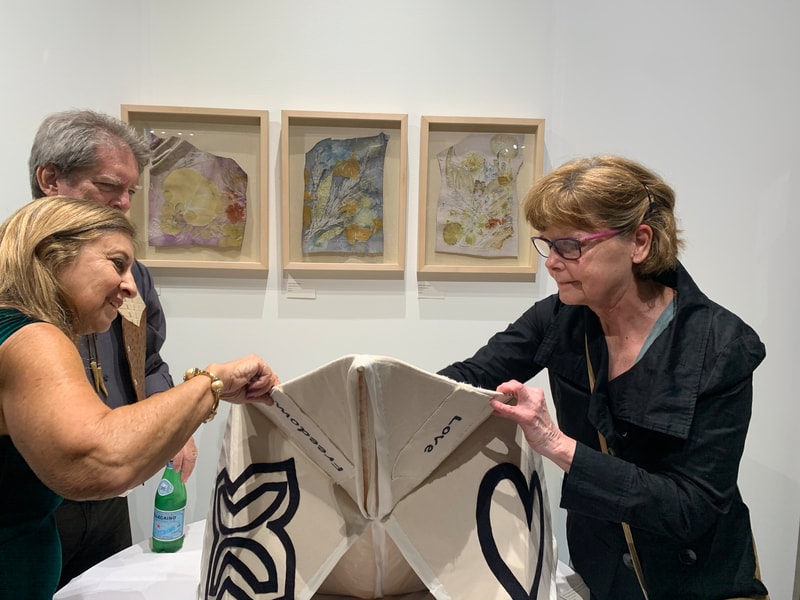 Visitors interacting with origami collaboration artwork at gallery