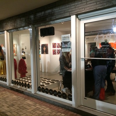 PRE_TEXTING — gallery storefront exterior at night with discs