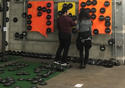 PRE_TEXTING — two visitors interacting with speech bubble wall installation in garage